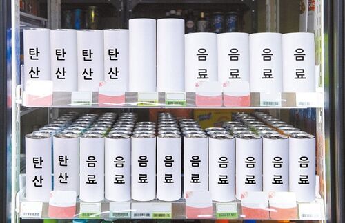 점자표기 없는 음료가 시각장애인에게 어떻게 느껴질지를 보여주는 가상의 이미지다. 두 줄의 흰색 음료캔들에 '탄산'이나 '음료'라는 글자가 쓰여 있다.