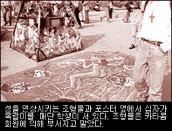 성을 연상시키는 조형물과 포스터 옆에서 십자가 목걸이를 매단 학생이 서 있다. 조형물을 카타콤 회원들에 의해 부서지고 말았다.