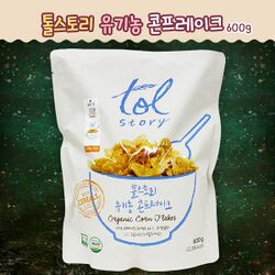 백색의 배경지 위에 파란 글씨로 Tol story라고 크게 쓰여 있다. 같은 색으로 그릇과 스푼이 그려져 있고, 그에 담긴 노란색 콘프레이크 제품이 눈에 들어온다.